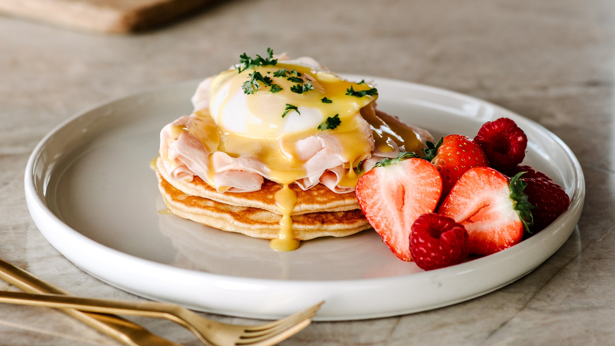 Amerískar pönnukökur með Ali silkiskorinni skinku, hleyptu eggi og hollandaise-sósu ásamt jarðarberjum og hindberjum á diski