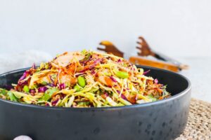 Stökkt kjúklingasalat með káli, gulrótum, edamame baunum, núðlum og sesamdressingu í svartri skál