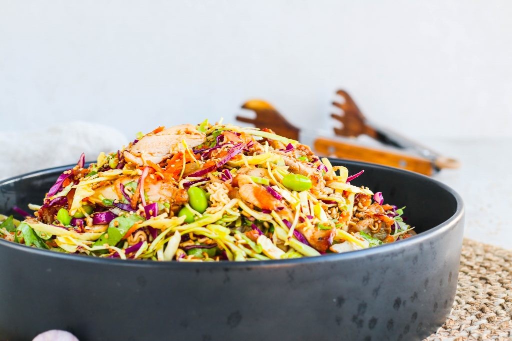 Stökkt kjúklingasalat með káli, gulrótum, edamame baunum, núðlum og sesamdressingu í svartri skál