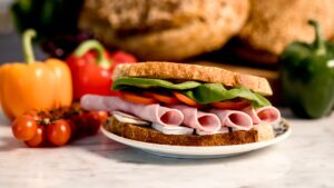 Súrdeigssamloka með Ali skinku, camembert, tómötum og spínati á diski